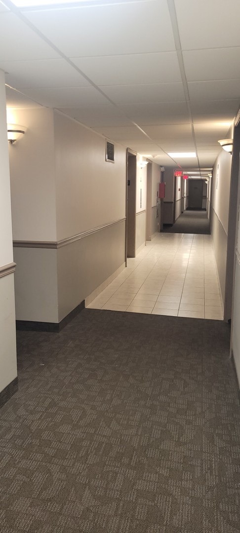 hallway with a paneled ceiling and carpet floors