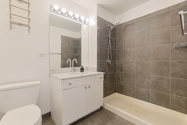 bathroom featuring toilet, vanity, tile patterned floors, and a tile shower