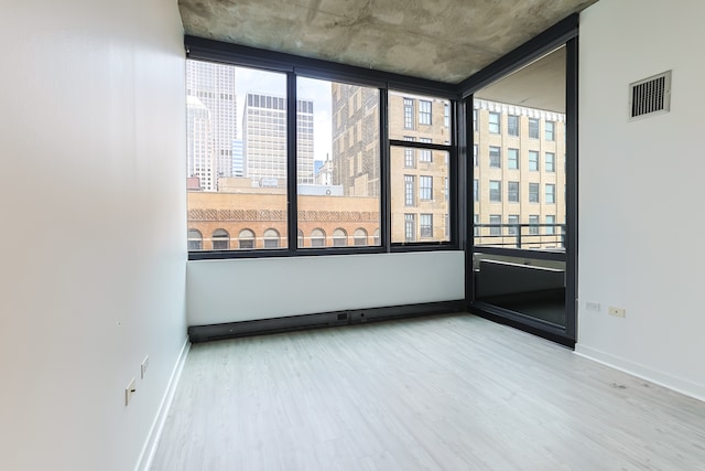 unfurnished room featuring a wall of windows, a wealth of natural light, and hardwood / wood-style flooring