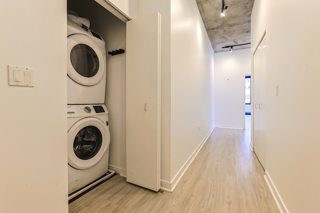 laundry room featuring stacked washer / drying machine and light hardwood / wood-style flooring