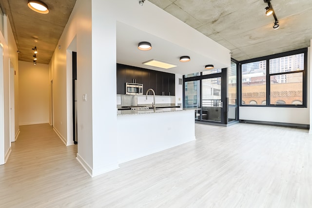 kitchen featuring kitchen peninsula, light hardwood / wood-style floors, sink, and light stone countertops