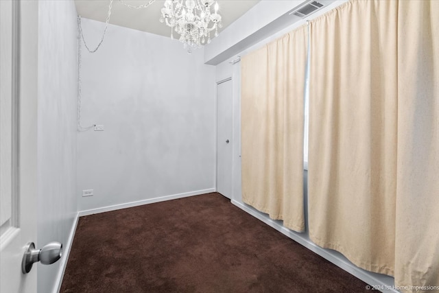 carpeted empty room featuring a notable chandelier