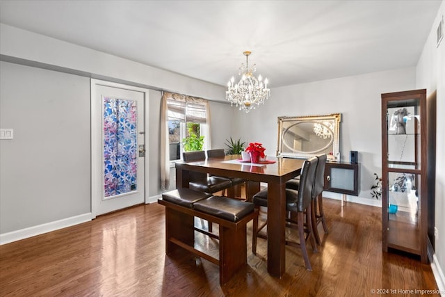 dining room with dark wood-type flooring and a chandelier