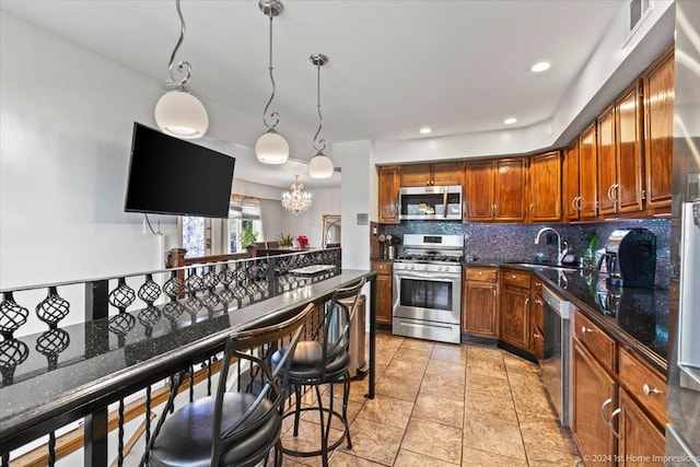 kitchen with backsplash, appliances with stainless steel finishes, pendant lighting, sink, and a chandelier