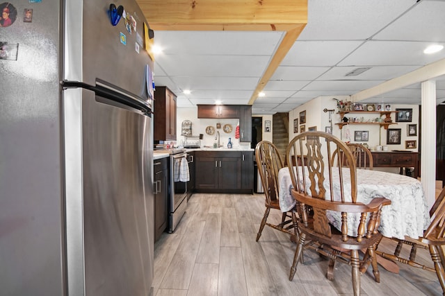 dining area featuring light hardwood / wood-style floors, sink, and a drop ceiling