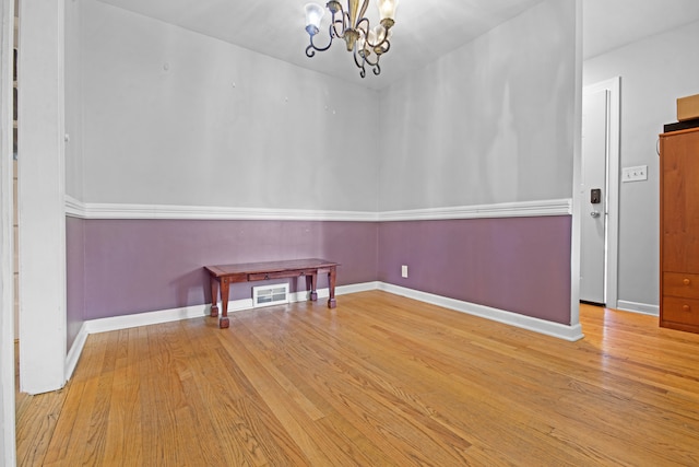 unfurnished room featuring a chandelier and light hardwood / wood-style floors