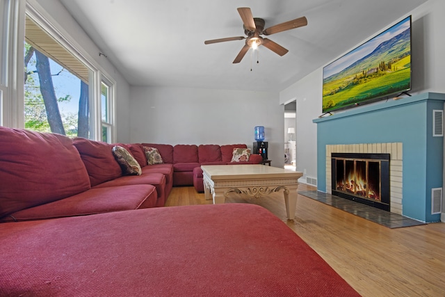 living room featuring a fireplace, ceiling fan, and light hardwood / wood-style flooring