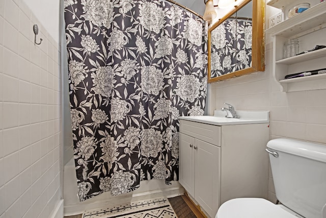 bathroom with curtained shower, vanity, toilet, and tile walls