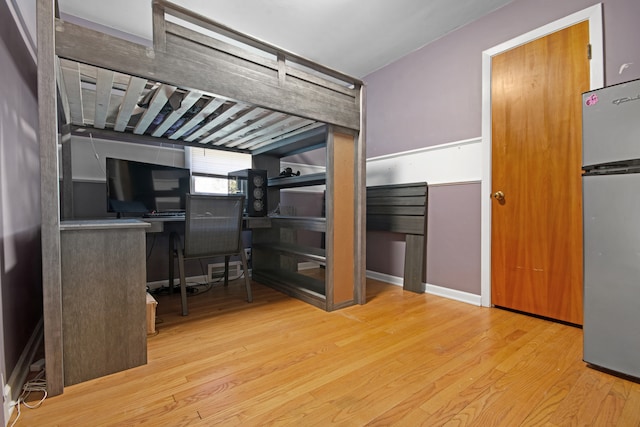 bedroom with stainless steel fridge and light wood-type flooring