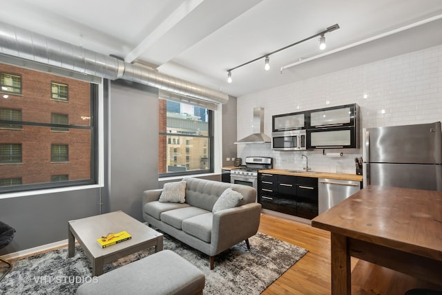 living room featuring light wood-type flooring, sink, and beam ceiling