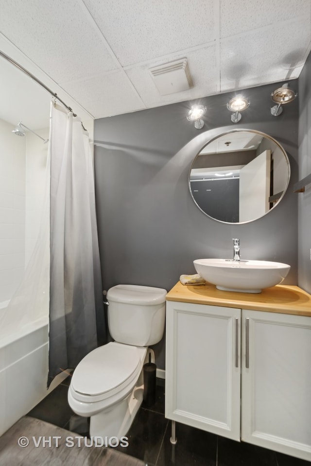 full bathroom featuring tile patterned flooring, a drop ceiling, shower / bathtub combination with curtain, vanity, and toilet