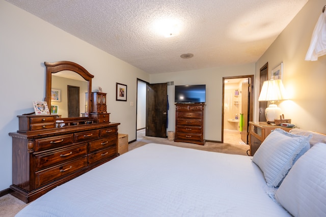 bedroom with ensuite bathroom, light colored carpet, and a textured ceiling