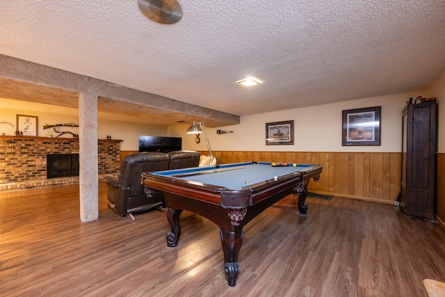 recreation room featuring hardwood / wood-style flooring, a textured ceiling, a fireplace, and billiards