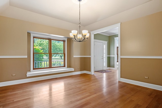 spare room with light hardwood / wood-style floors, crown molding, and an inviting chandelier