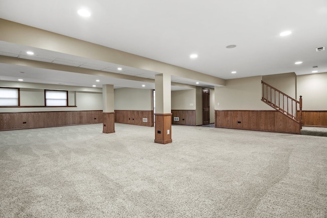 basement with light carpet and wooden walls