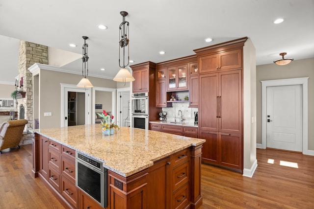 kitchen with a center island, hardwood / wood-style floors, hanging light fixtures, sink, and appliances with stainless steel finishes