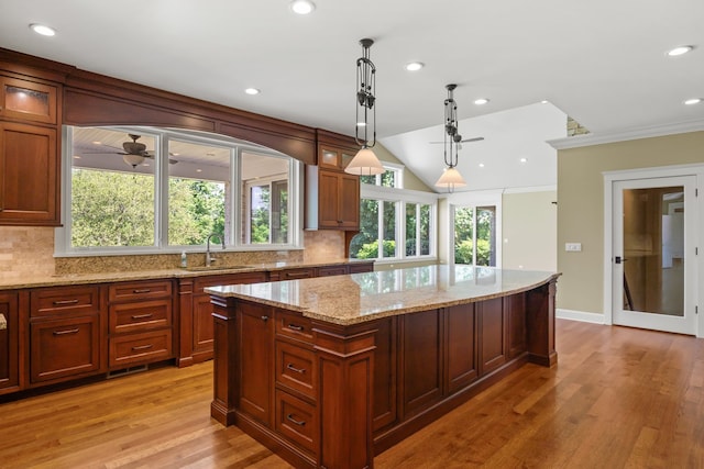 kitchen with sink, decorative light fixtures, a kitchen island, and light hardwood / wood-style flooring