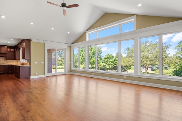 unfurnished living room with high vaulted ceiling, sink, hardwood / wood-style flooring, and ceiling fan