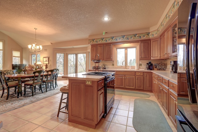 kitchen with black range oven, pendant lighting, a chandelier, a center island, and plenty of natural light