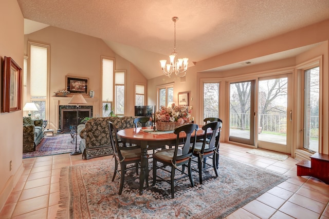 dining area featuring a textured ceiling, a high end fireplace, light tile patterned floors, and vaulted ceiling