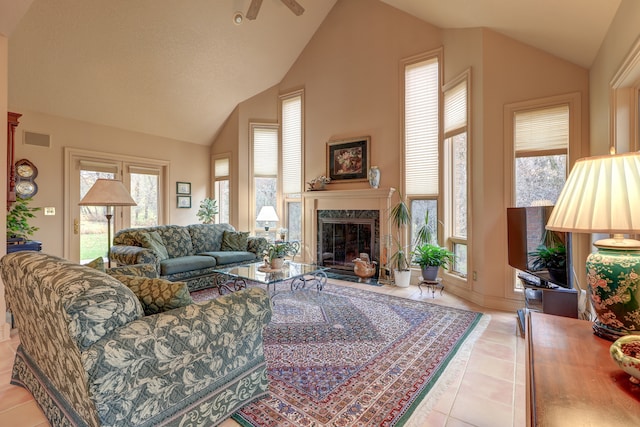 living room featuring ceiling fan, a fireplace, light tile patterned floors, and vaulted ceiling