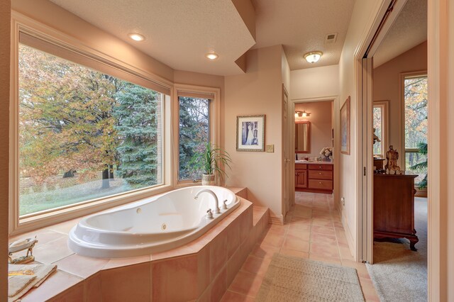 bathroom featuring tiled tub, tile patterned flooring, vanity, and a textured ceiling