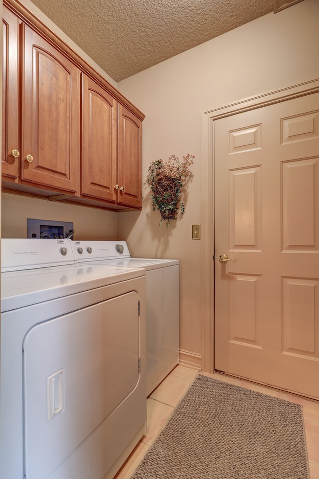 laundry area featuring cabinets, independent washer and dryer, a textured ceiling, and light tile patterned floors