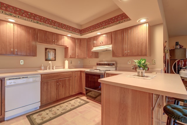 kitchen with a breakfast bar area, kitchen peninsula, sink, and white appliances