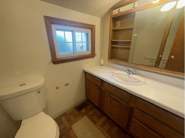 bathroom featuring vanity, parquet floors, and toilet