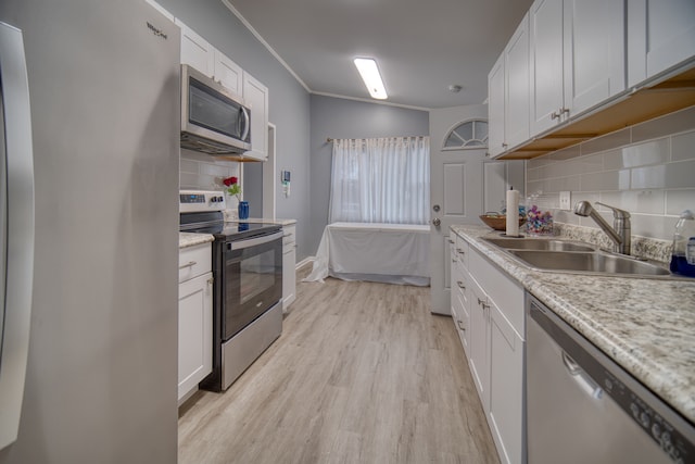 kitchen with light hardwood / wood-style floors, decorative backsplash, sink, white cabinetry, and appliances with stainless steel finishes