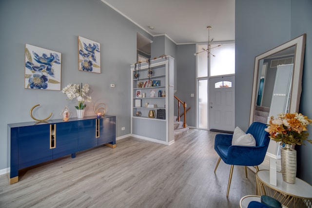 entryway featuring a high ceiling, light wood-type flooring, a chandelier, and crown molding