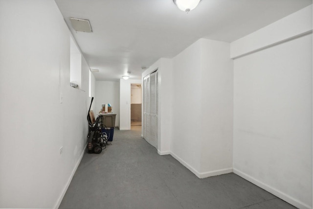 hall featuring concrete floors and baseboards