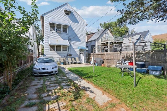 rear view of house featuring a yard and fence