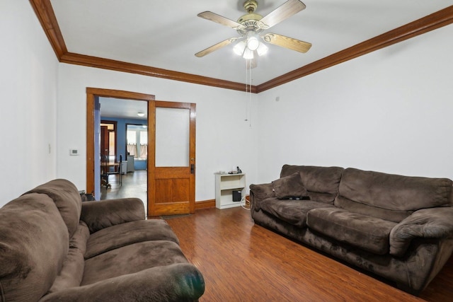 living area with a ceiling fan, dark wood-type flooring, crown molding, and baseboards