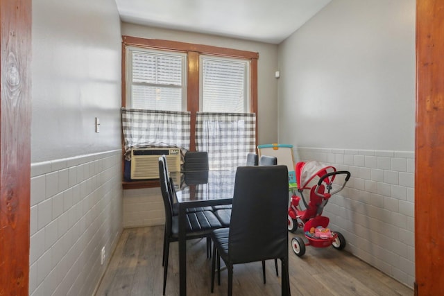 dining room with wainscoting, cooling unit, tile walls, and wood finished floors