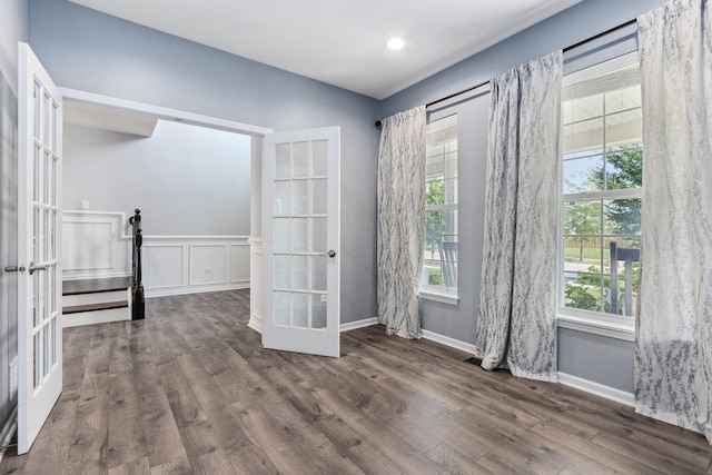 spare room with french doors, plenty of natural light, and dark wood-type flooring