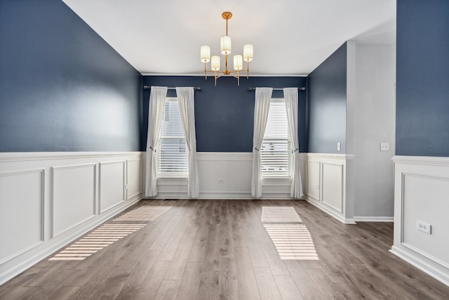 unfurnished dining area featuring an inviting chandelier and hardwood / wood-style floors