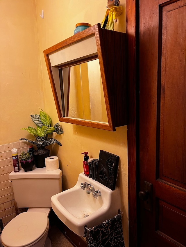 bathroom featuring tile walls, sink, and toilet