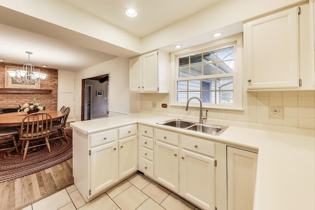 kitchen with light countertops, a sink, a peninsula, and white cabinetry