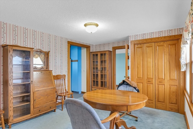 dining area with light carpet and a textured ceiling