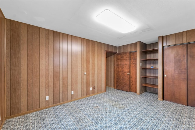 unfurnished bedroom featuring multiple closets and wood walls