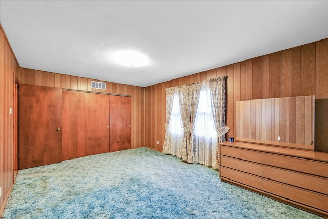 interior space with carpet flooring, a closet, and wooden walls