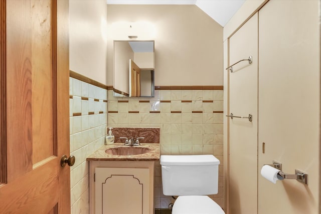 bathroom featuring vaulted ceiling, vanity, tile walls, and toilet