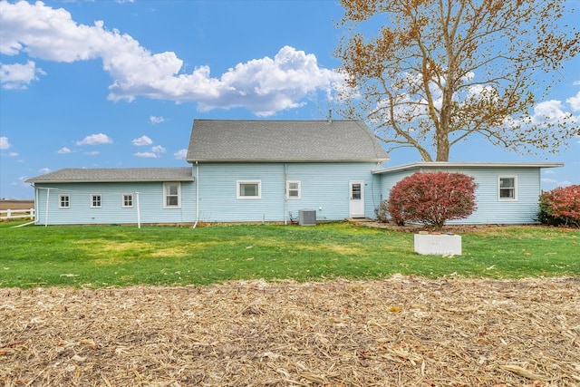 back of house with central air condition unit and a yard