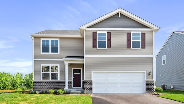 view of front of property with a front lawn, a garage, and central AC