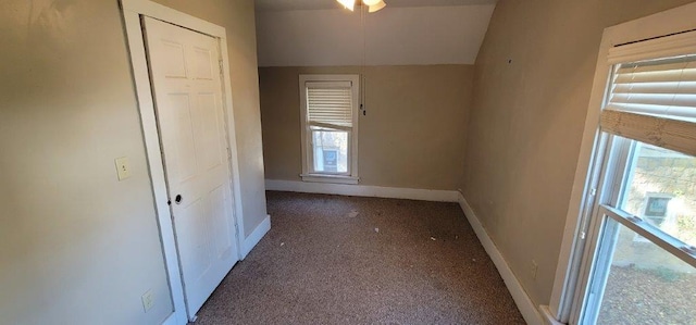 corridor with dark carpet and vaulted ceiling