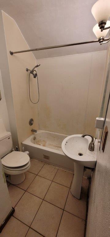 bathroom with toilet, tile patterned floors, and washtub / shower combination