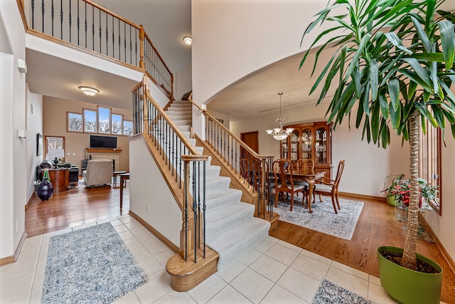 stairway with a high ceiling, a notable chandelier, and hardwood / wood-style flooring