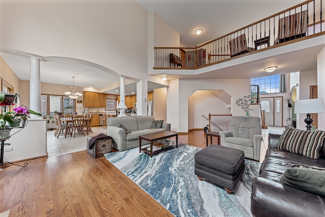 living room with a wealth of natural light, light hardwood / wood-style flooring, a chandelier, and a high ceiling