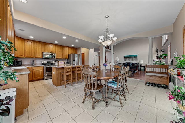 dining area with decorative columns, light tile patterned floors, and an inviting chandelier